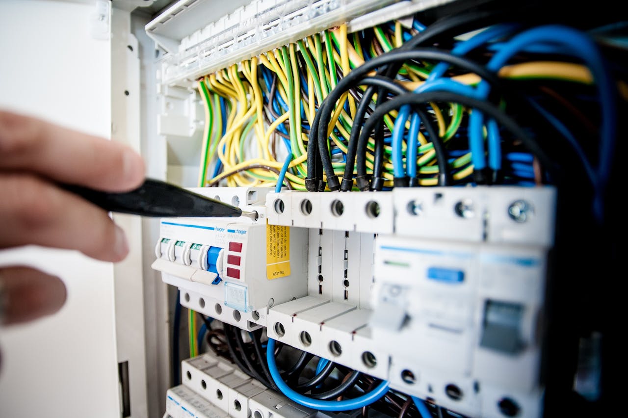 digital Hand of electrician working on a circuit breaker panel with colorful wires, ensuring safe electrical connections.