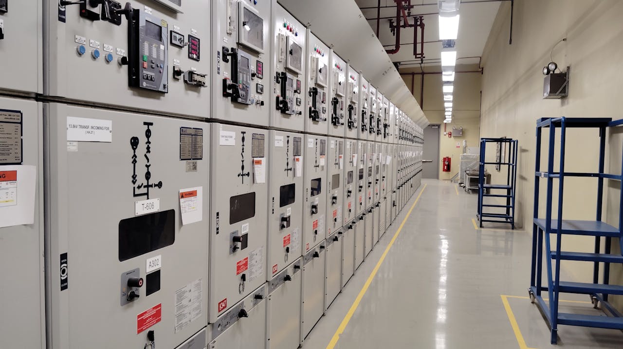 Services-03 Long row of control panels in an industrial electrical control room, well-lit and spacious.